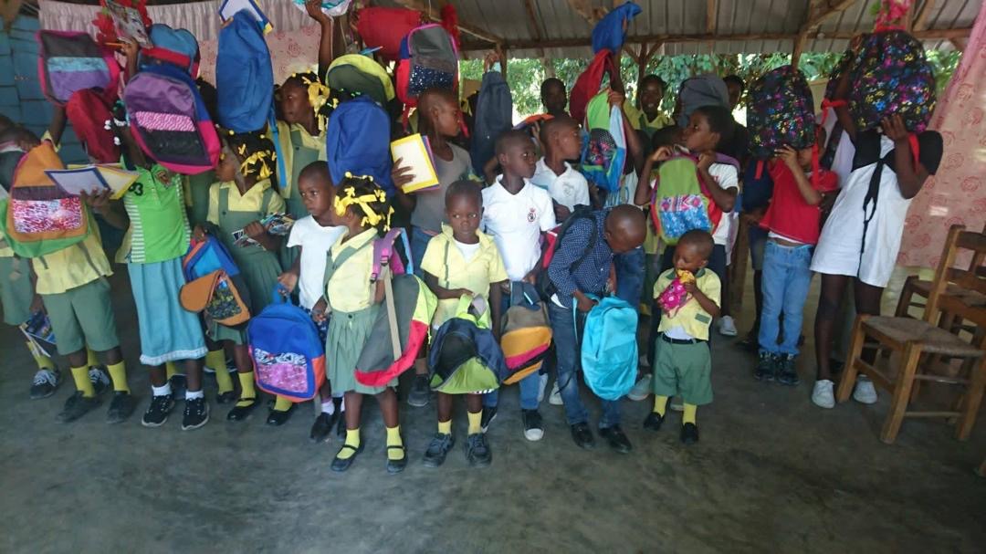Children proudly holding up new backpacks